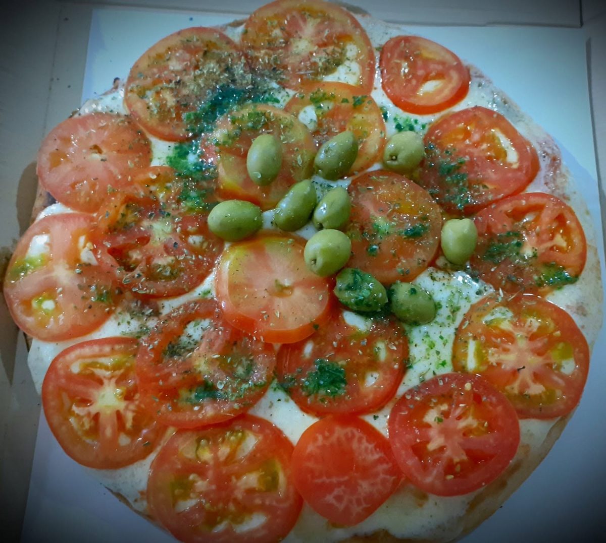 Pizza napolitana con rodajas de tomate y aceitunas verdes